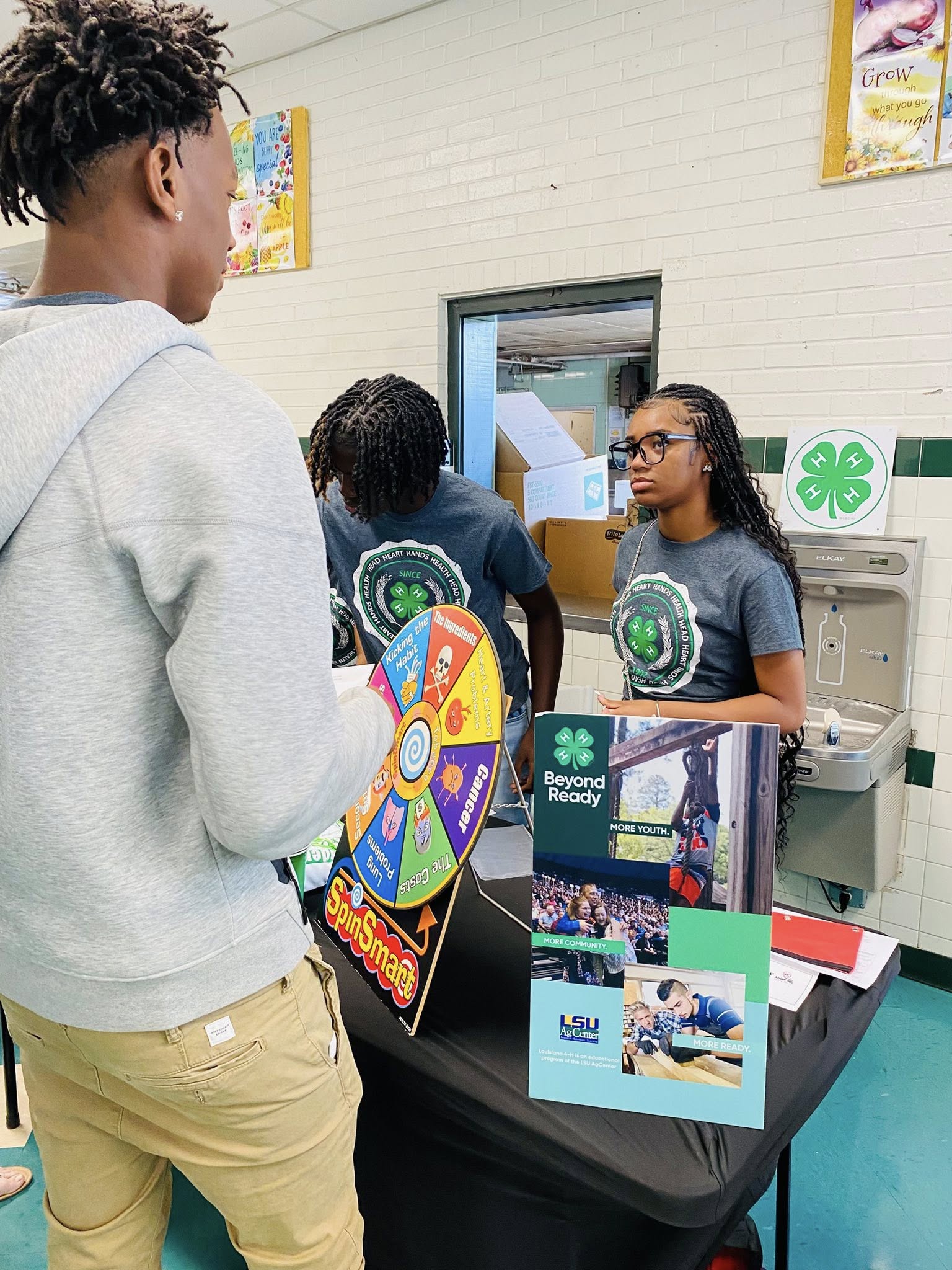 A teenage boy and a teenage girl standing by a table filled with 4-H items.